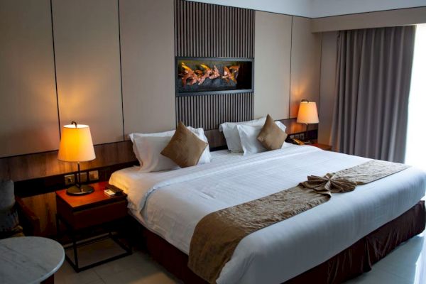 A cozy hotel room with a large bed, two lamps, decorative pillows, and a wall art piece, creating a warm and inviting atmosphere.