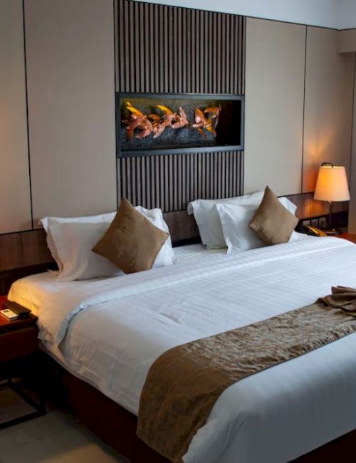 A cozy hotel room with a large bed, bedside lamps, neutral tones, and elegant decor, creating a warm and inviting atmosphere.
