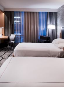 A modern hotel room with two beds, a flat-screen TV, a work desk, and stylish decor.