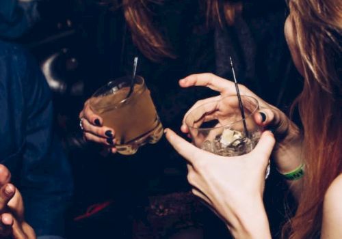 People are at a lively gathering, holding drinks and chatting.