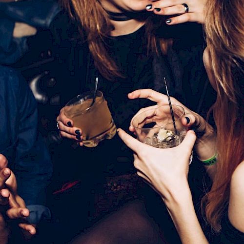 People are at a lively gathering, holding drinks and chatting.