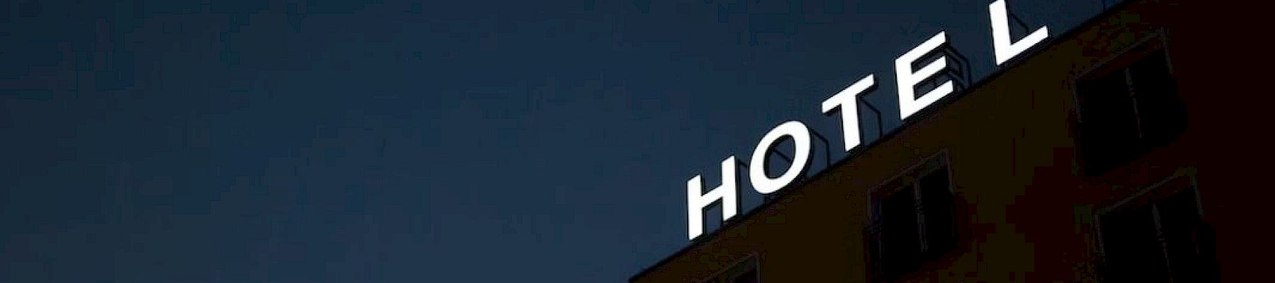 A building at night displays a sign saying "HOTEL" with the letter "L" not fully illuminated against a dark sky.