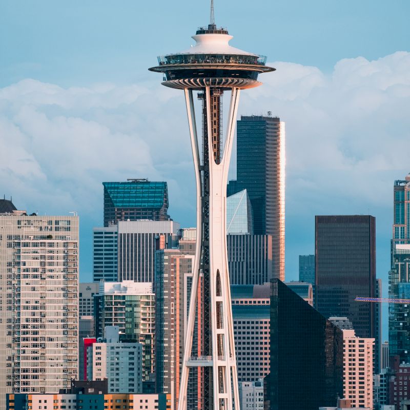 The image shows the Seattle skyline with the Space Needle prominently in the foreground, surrounded by various modern skyscrapers.